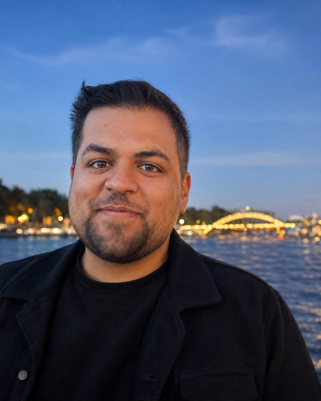 Editorial portrait of Dominic Madera beside a waterfront at blue hour